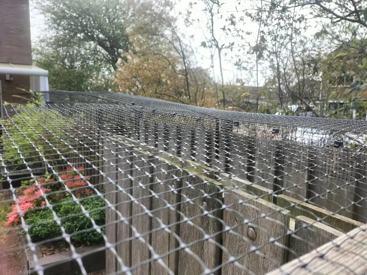Kattennet met clips bevestigd op schutting in de tuin