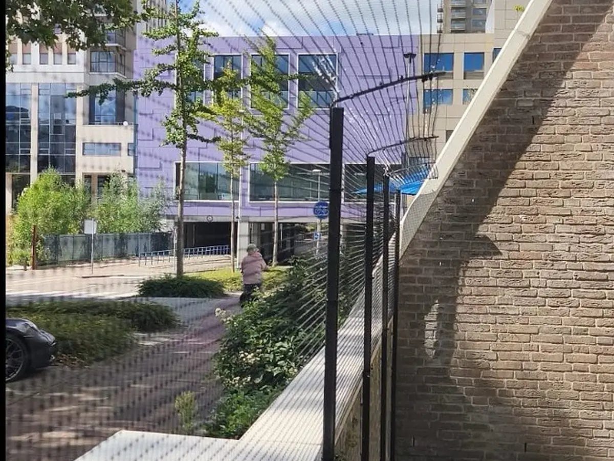 Kattennet langs bakstenen muur van een smalle stadstuin